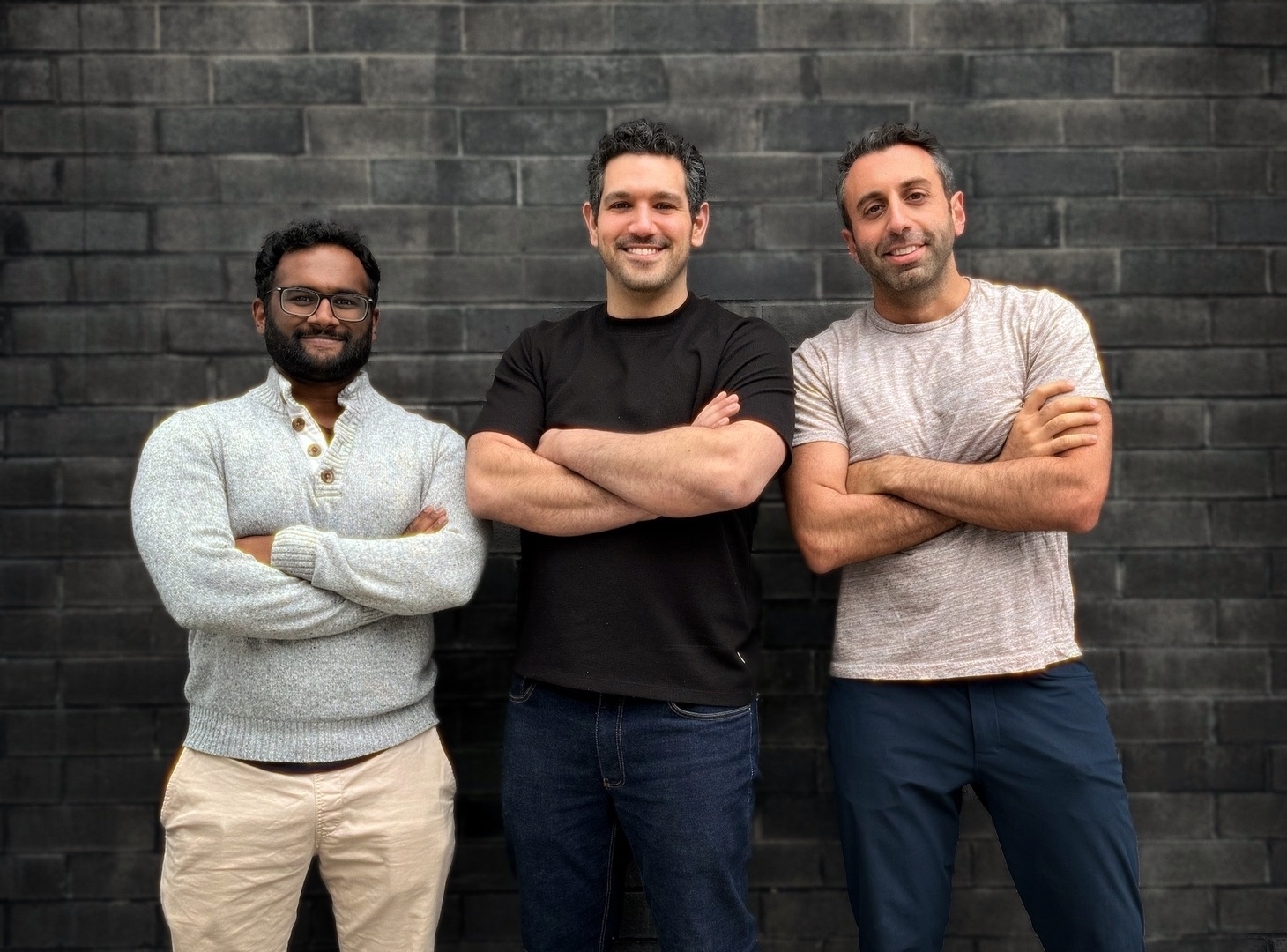 The ChatFeatured founding team standing together in front of a dark brick wall